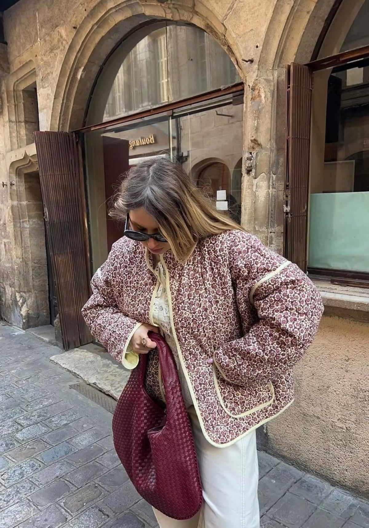 Veste matelassée fleurie prune portée en extérieur avec un jean