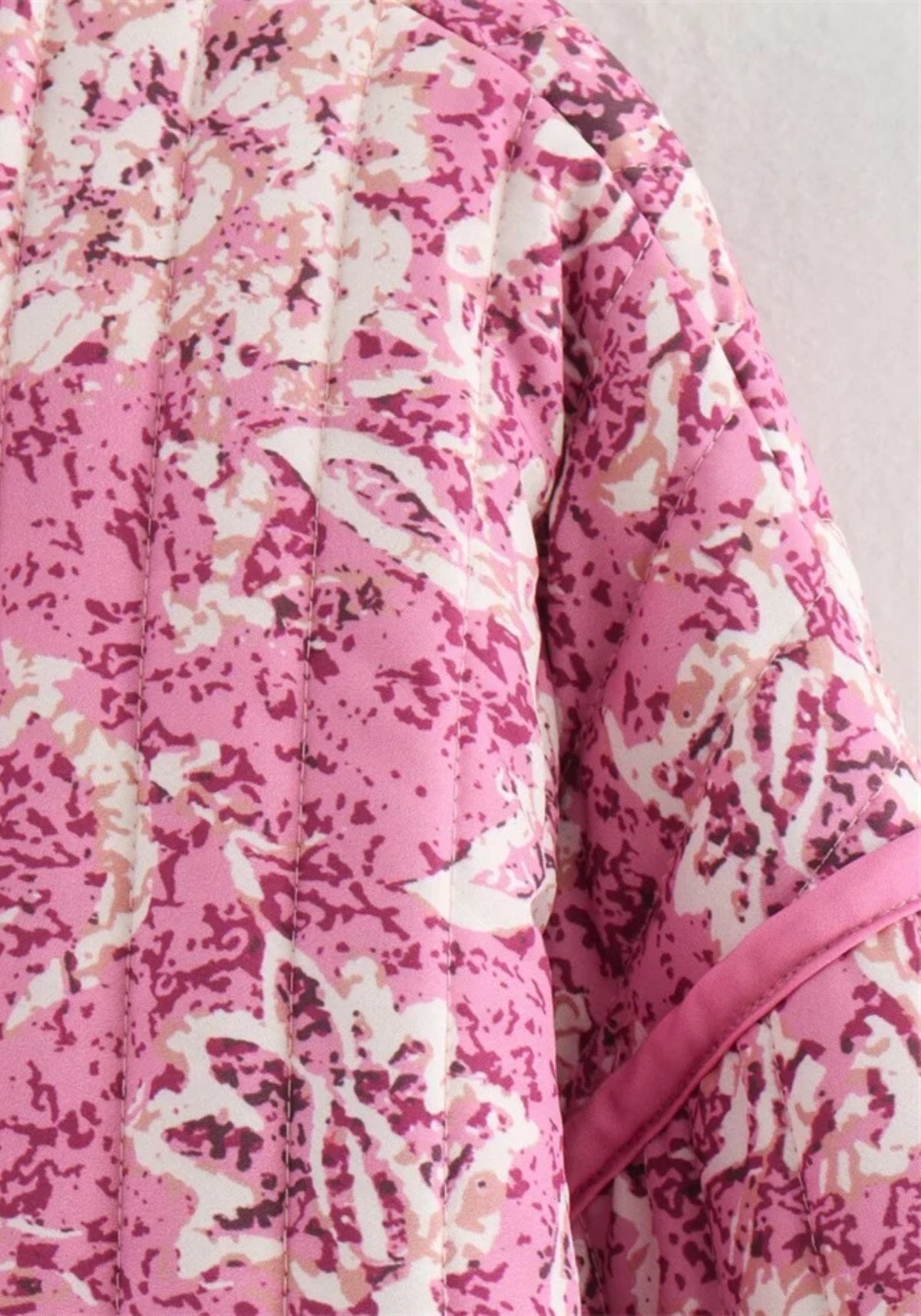 Détail du motif floral blanc sur fond rose framboise matelassé